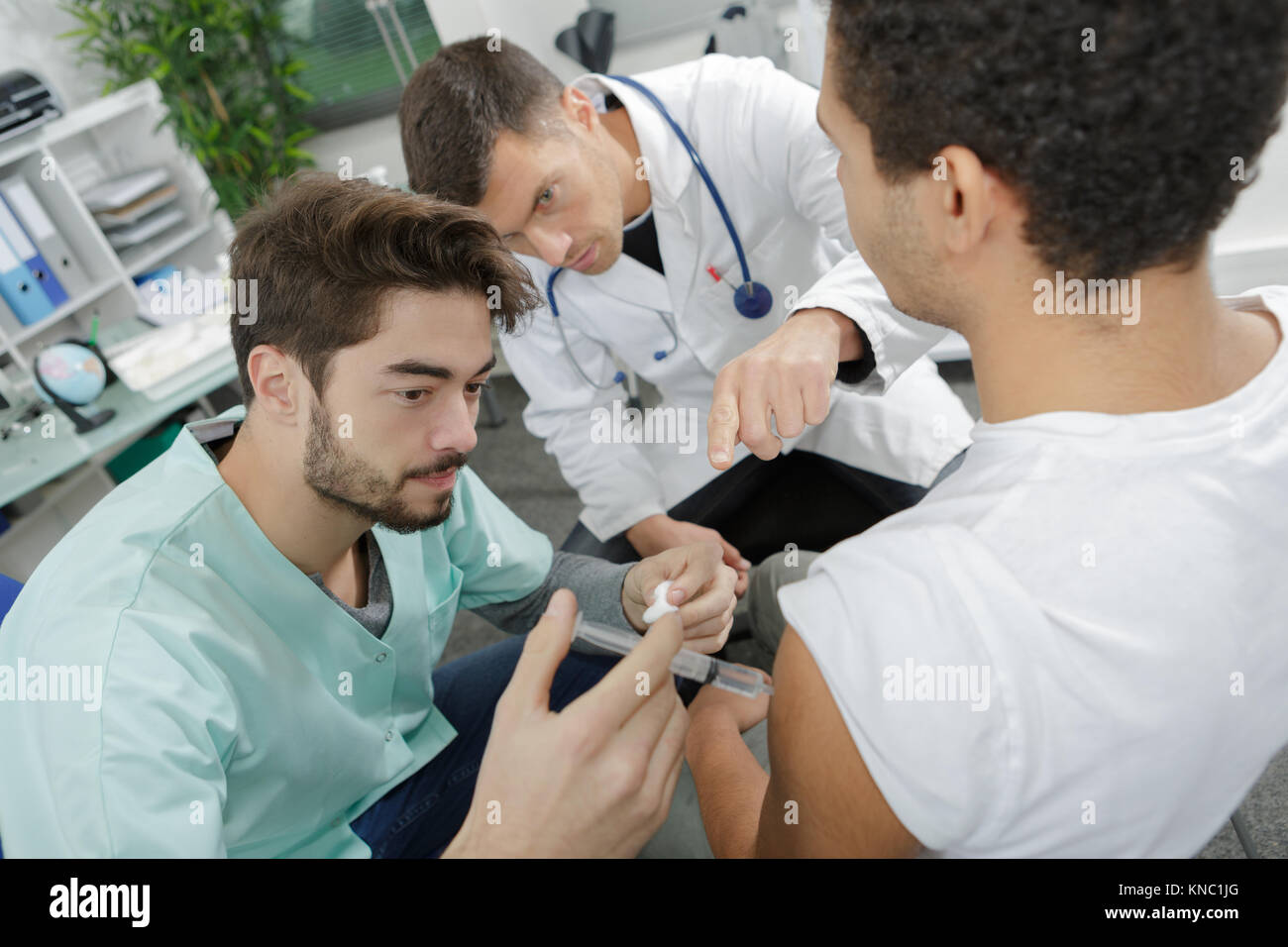 handsome intenrist injecting patient under mature doctors surveillance Stock Photo