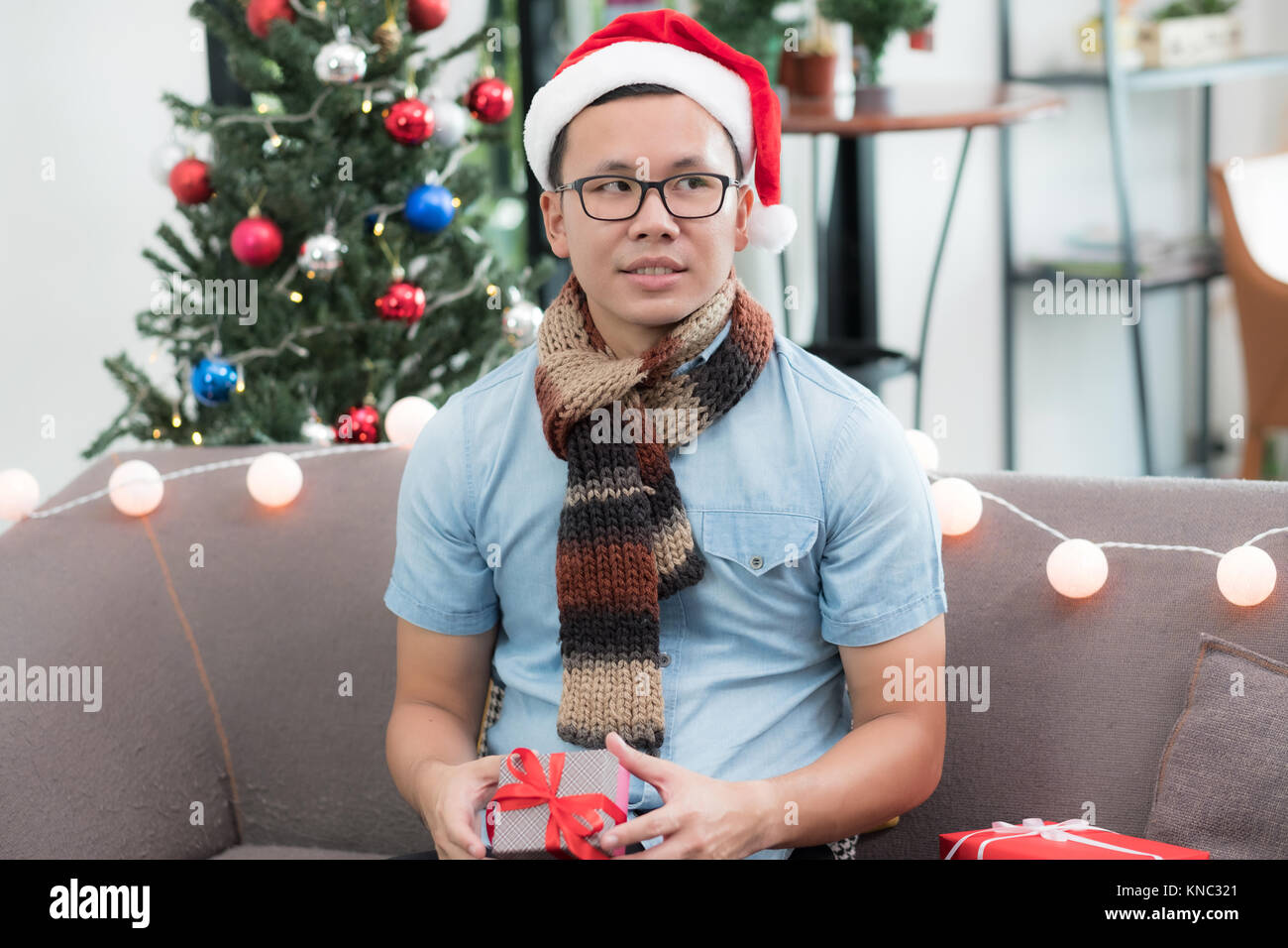 Asia man holding small gift box and looking at friend feel envious of other bigger present and sit alone on sofa,jealous and lonely emotion Stock Photo