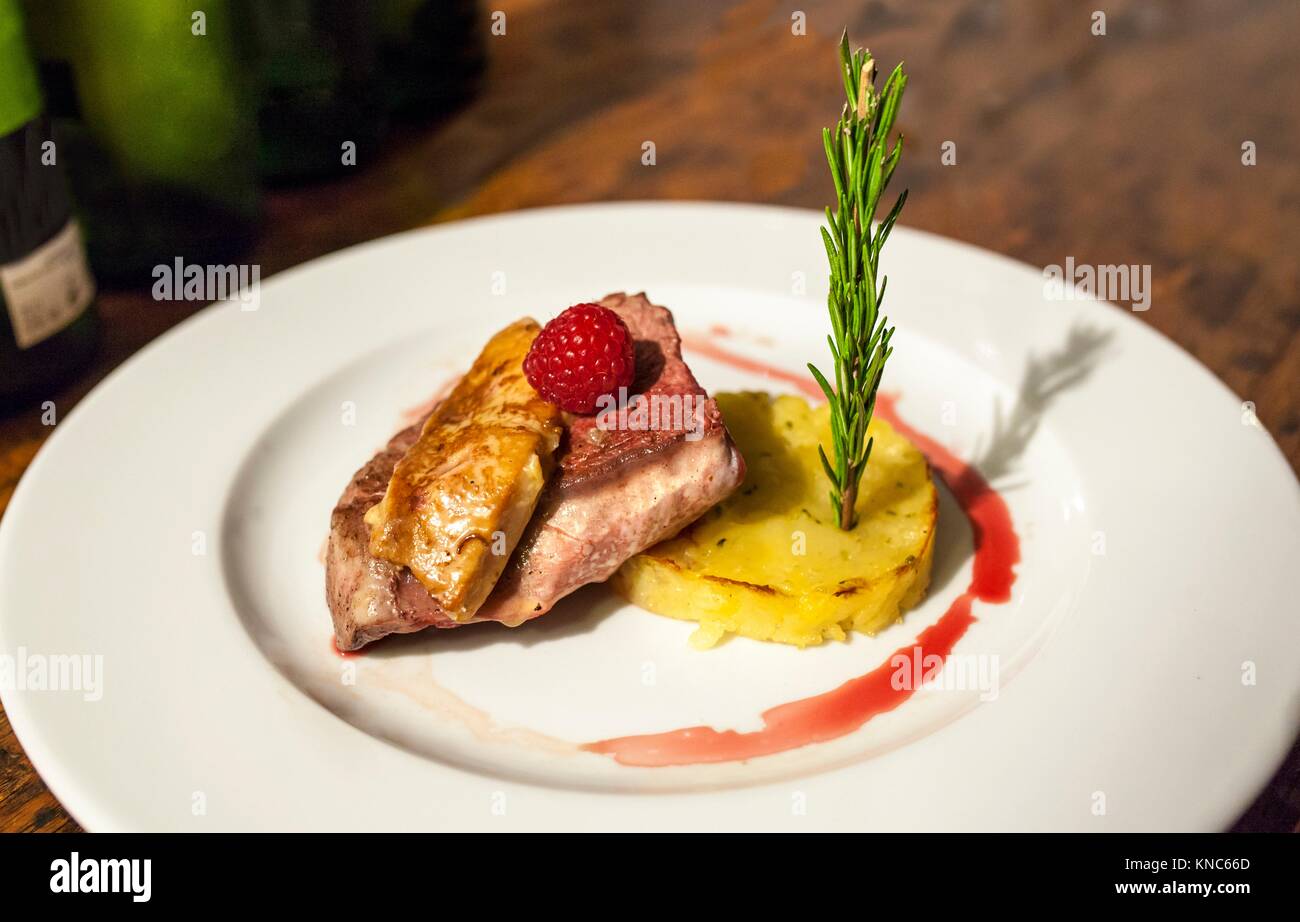Grilled veal tenderloin with berries, potatoes au gratin, foie and rosemary branch. Closeup. Stock Photo