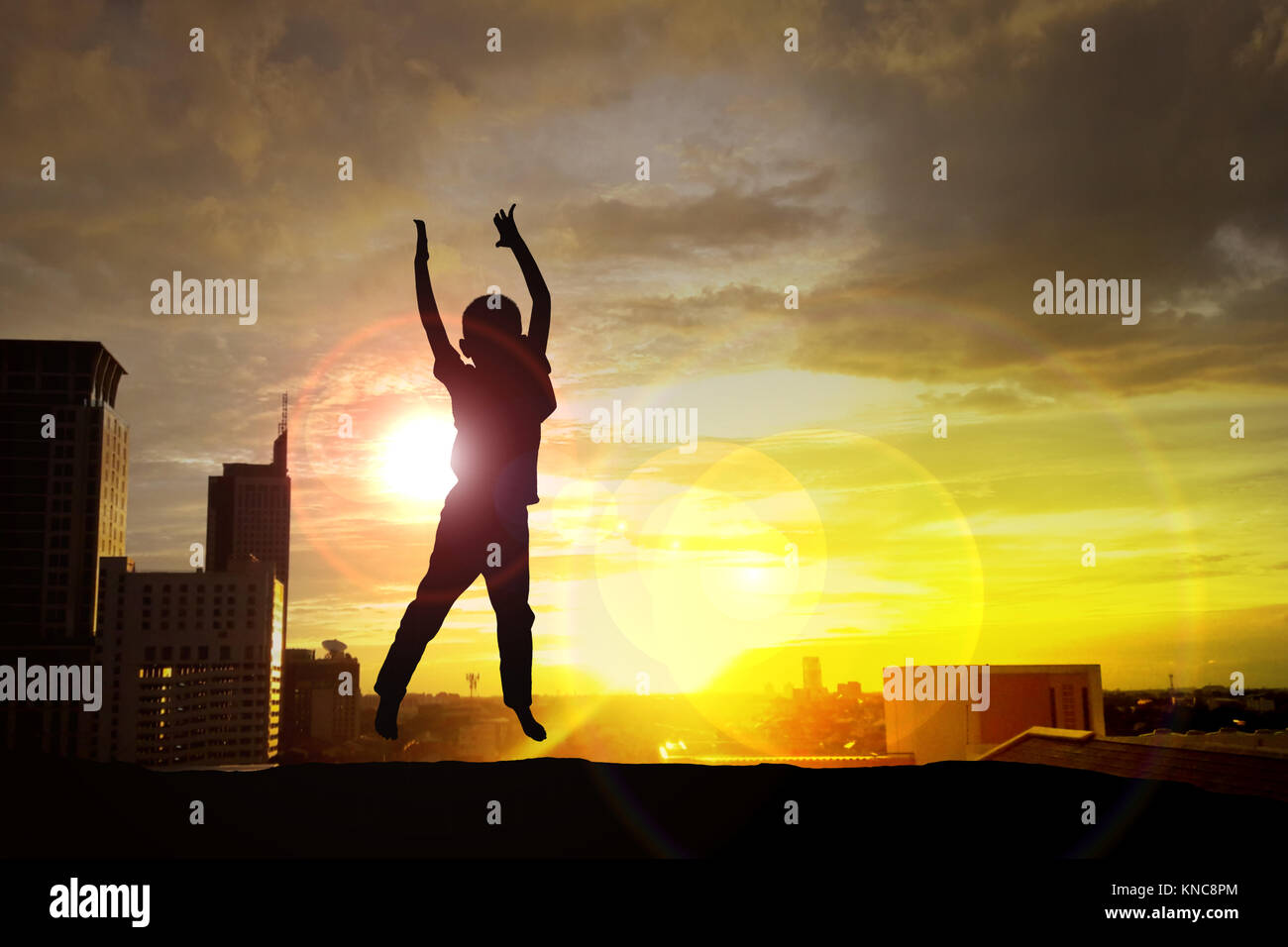 silhouette of happy kid jumping on the building at sunset Stock Photo