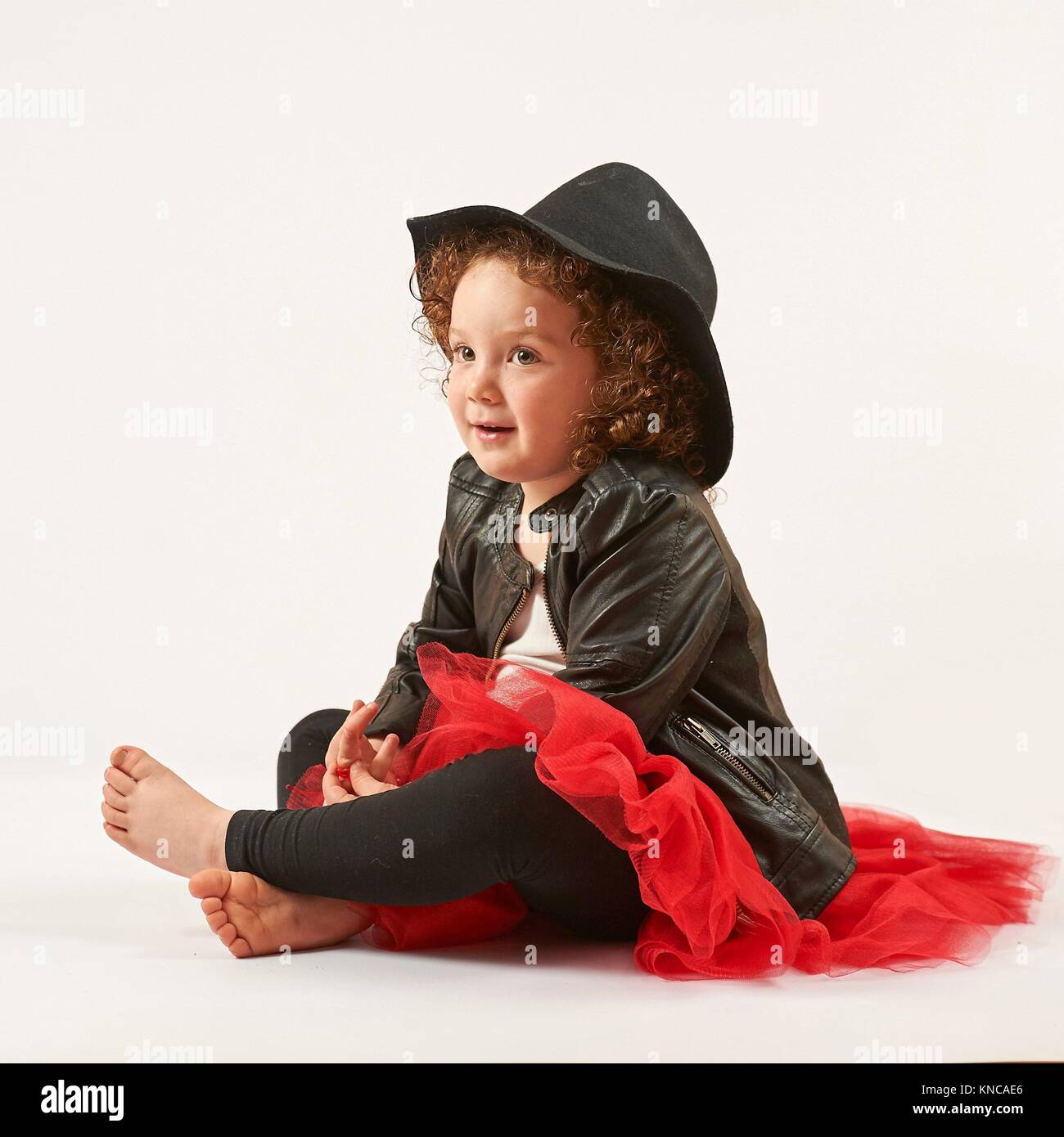 Little girl with black hat sitting and dreams. Stock Photo
