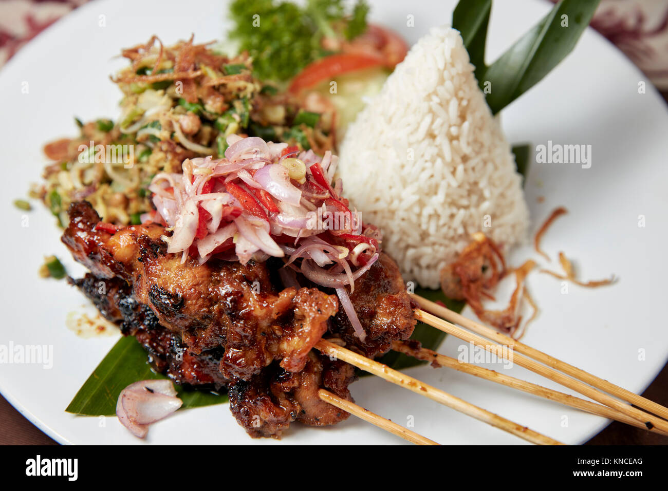 Balinese Pork Satay (Sate Babi) with rice and vegetables served in a local warung (small  restaurant). Bali, Indonesia. Stock Photo