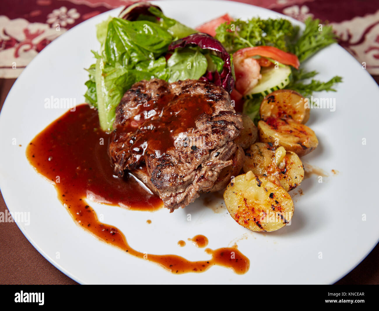 Grilled sirloin beef steak with potato wedges and green salad served in a local warung (small  restaurant). Bali, Indonesia. Stock Photo