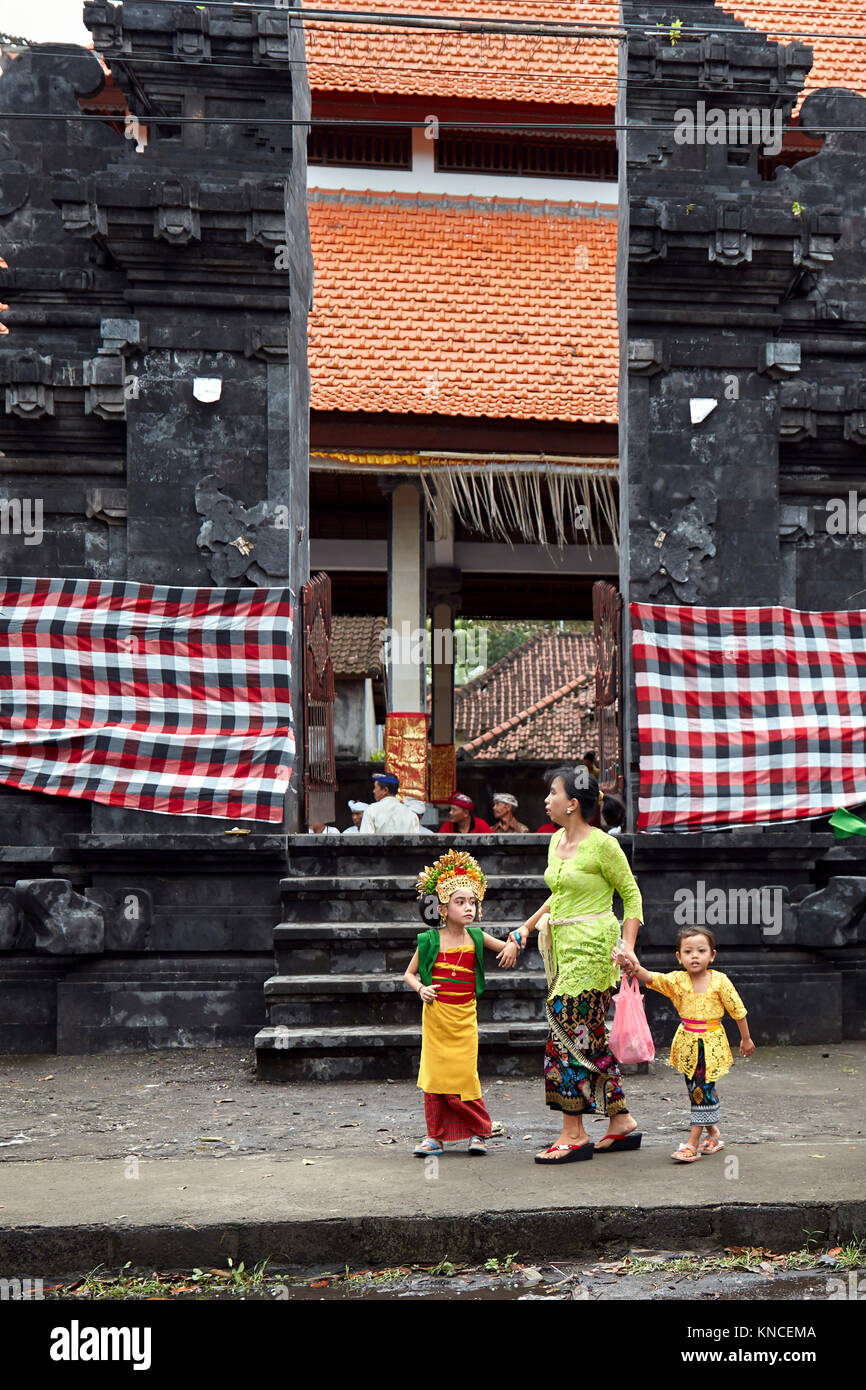 Woman with children wearing traditional Balinese clothing go to a local temple near Bugbug village. Karangasem Regency, Bali, Indonesia. Stock Photo