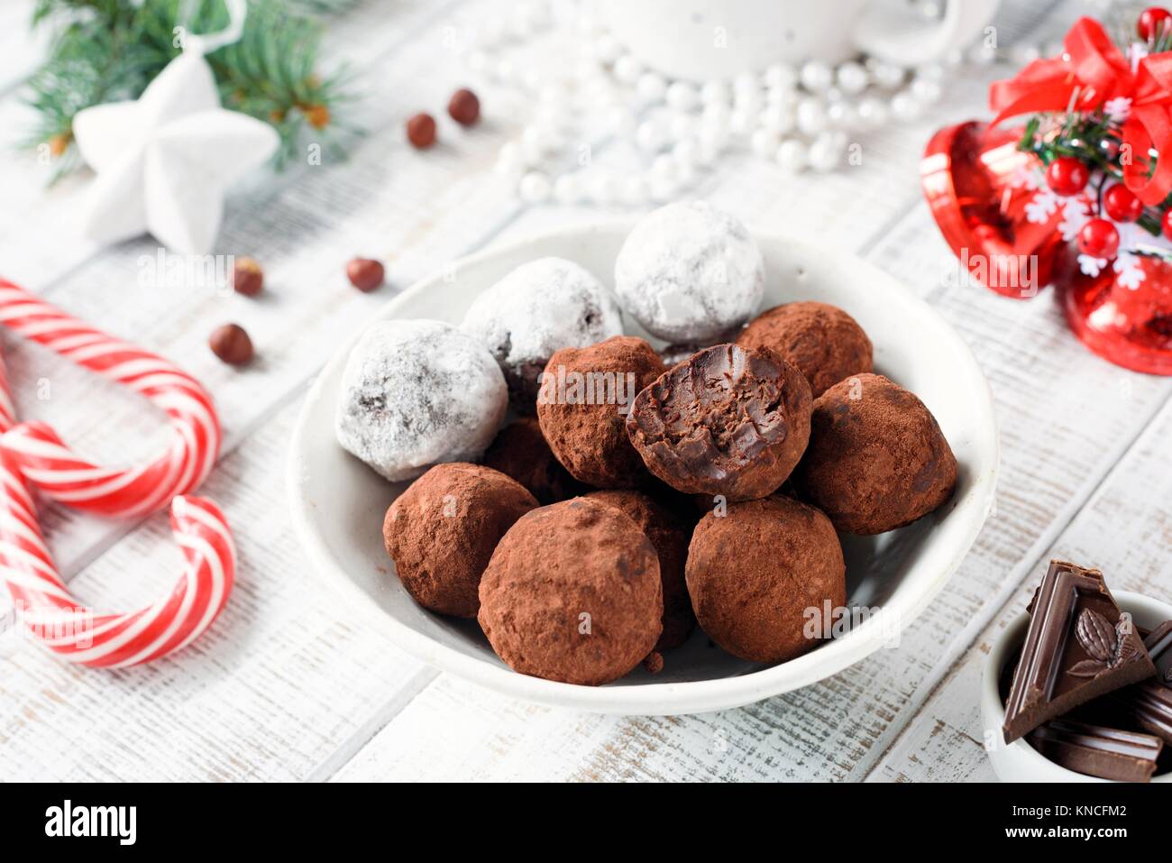 Homemade chocolate candy truffles with candy canes on white table. Christmas sweets. Closeup view Stock Photo