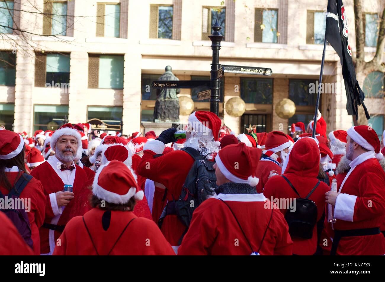 Flash mob dressed as Santa Claus walking through London, drinking and making merry for Santacon 2017 in North London, King's Cross area Stock Photo