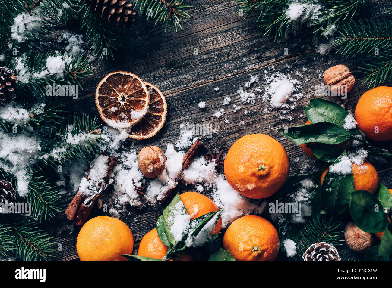 Christmas or New Year wallpaper background with tangerines, fir tree, spices and snow on old wood. Top view, toned image and copy space for text Stock Photo