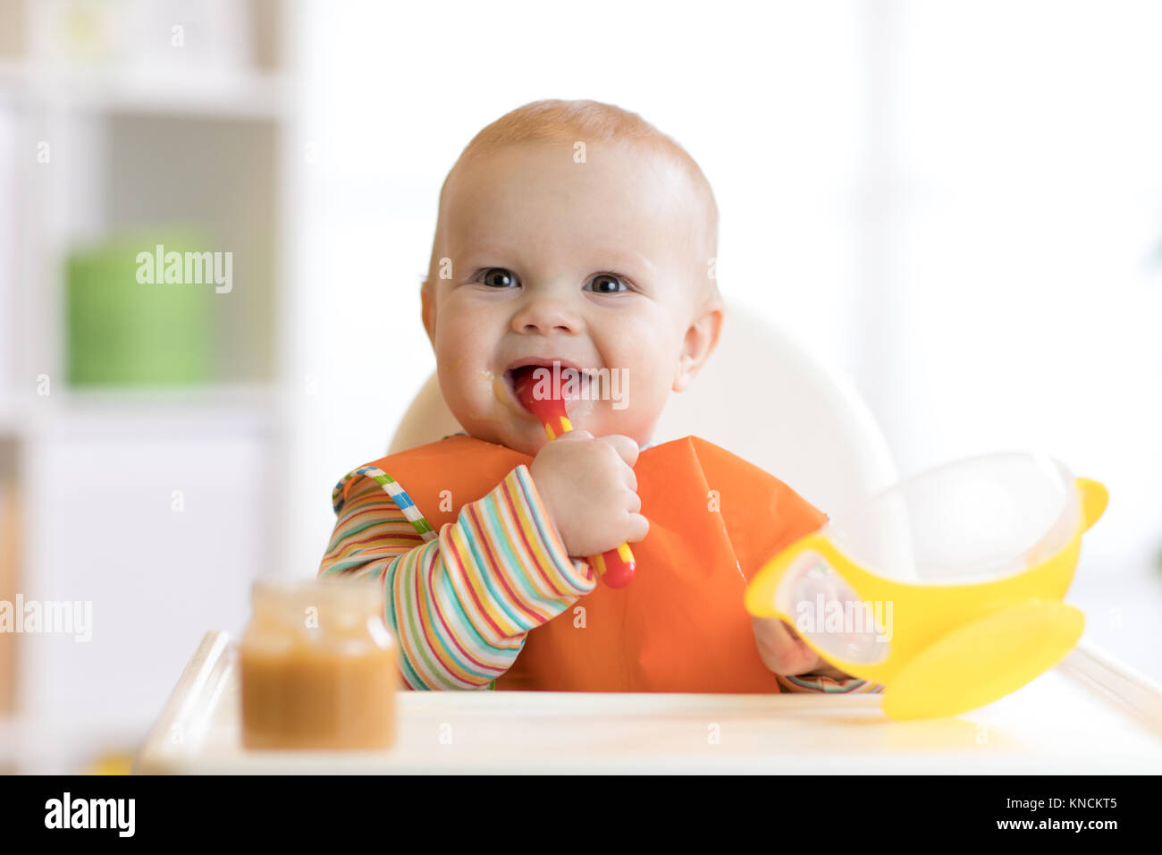 Happy infant baby boy spoon eats itself Stock Photo