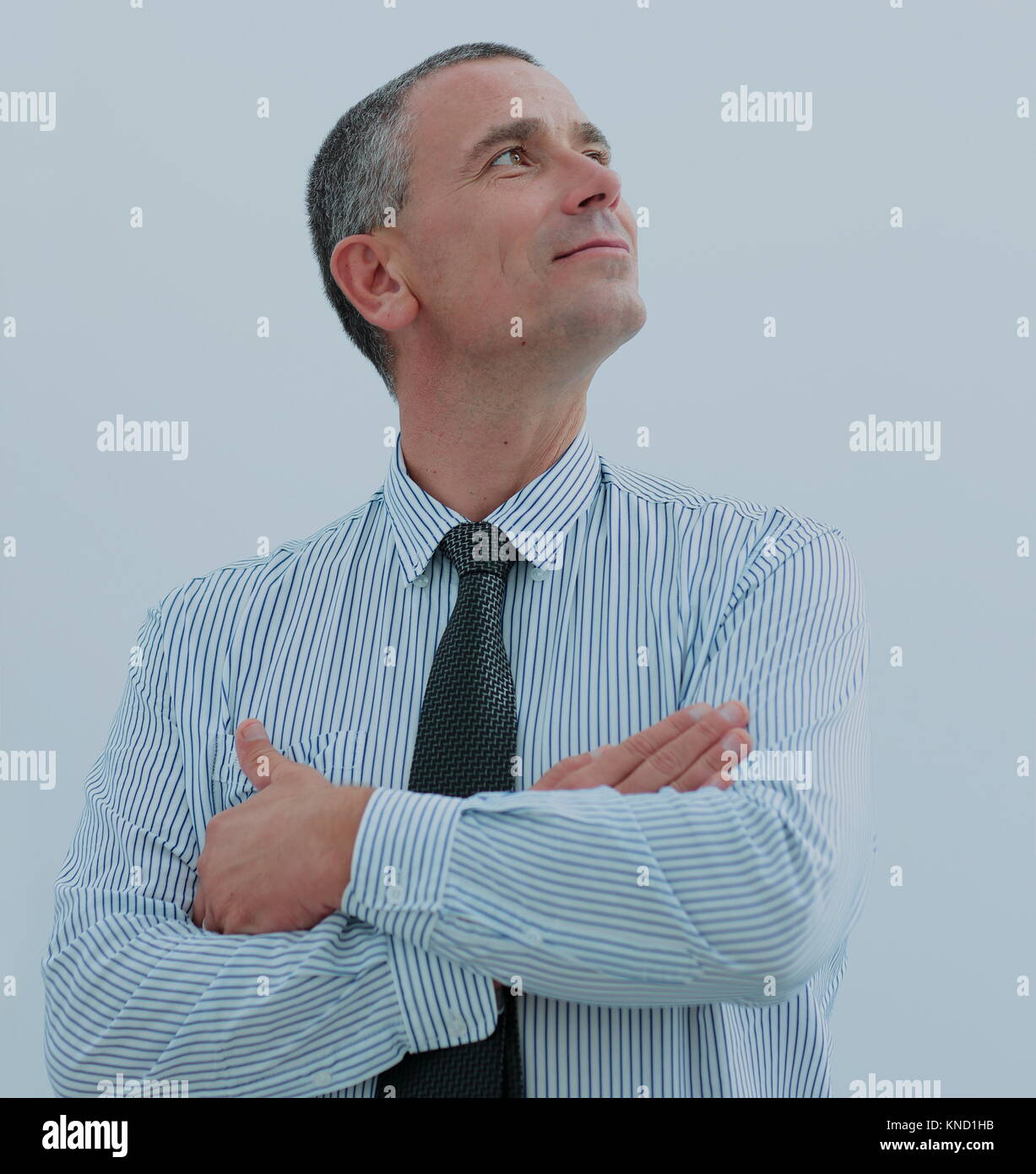 portrait of a positive businessman with arms crossed in front of him ...