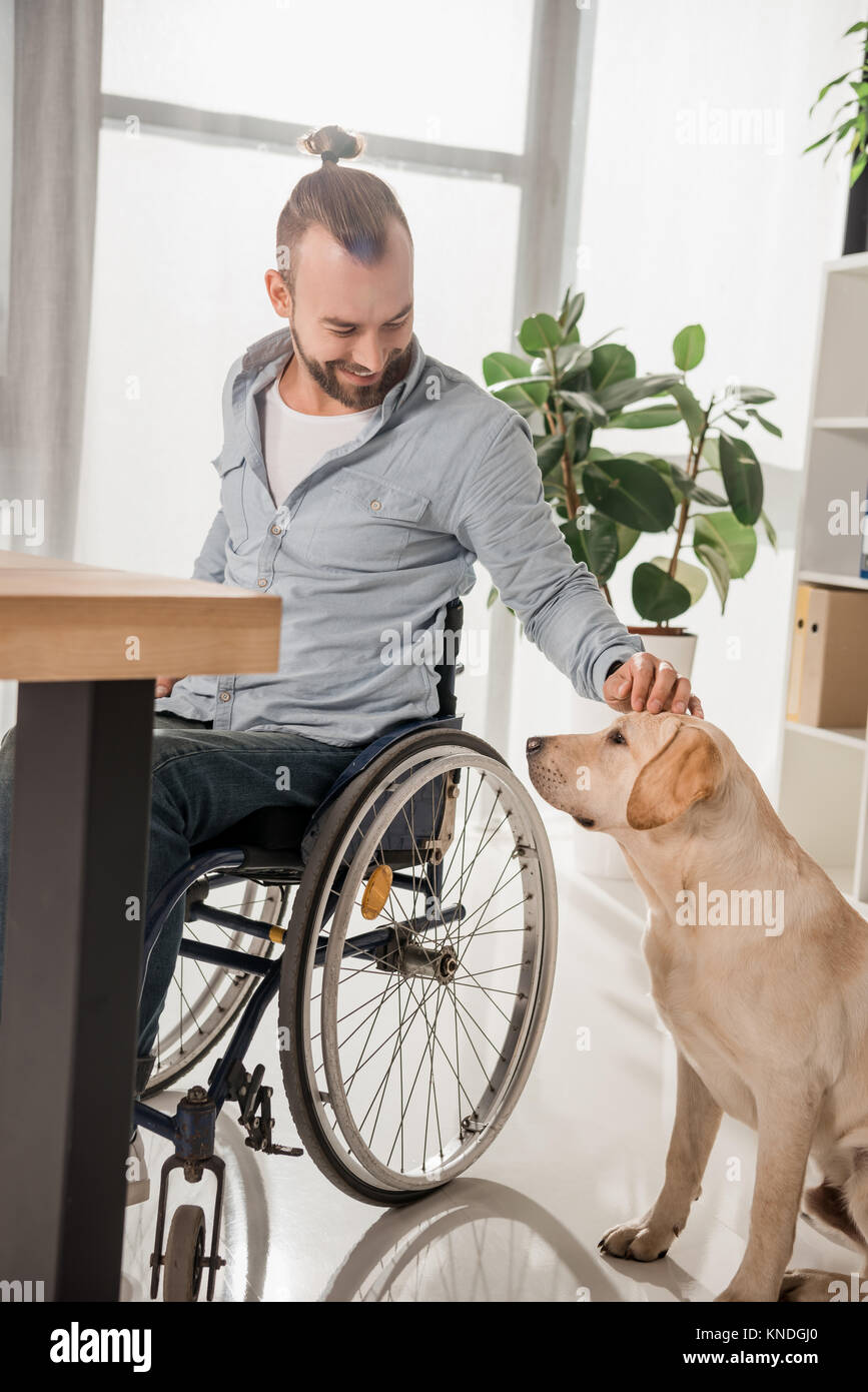 man on wheelchair petting his dog Stock Photo