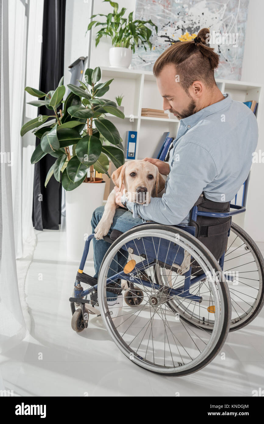 man on wheelchair petting his dog Stock Photo