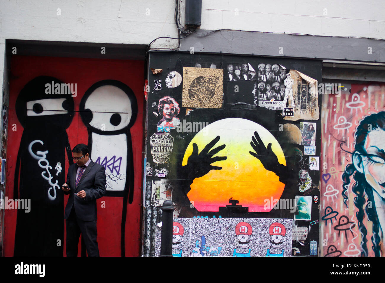 Man smoking while using his mobile phone near Brick Lane in east London Stock Photo