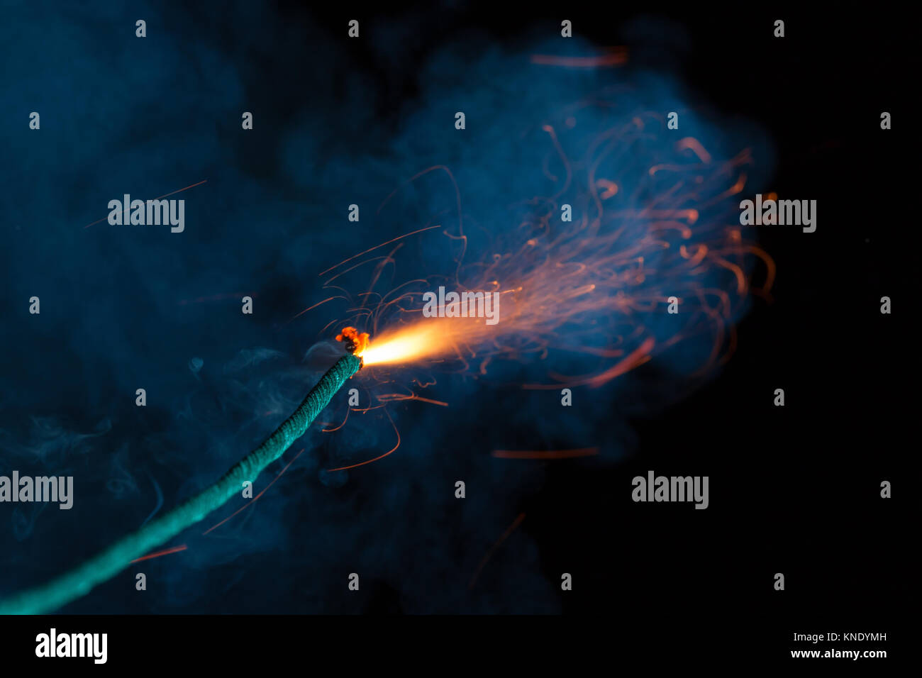 Burning fuse with sparks and lots of blue smoke on black background Stock Photo
