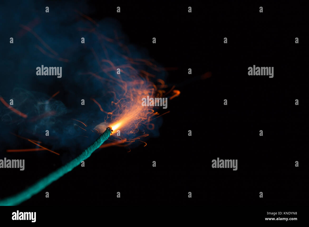 Burning fuse with sparks and blue smoke on black background Stock Photo