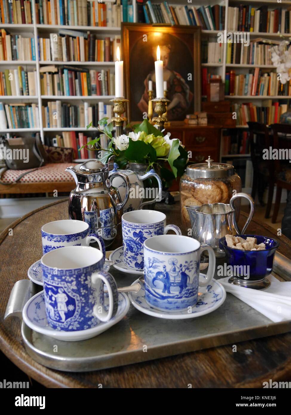 Close up of tea tray with fine china cups and saucers in cosy library with bookshelves in background Stock Photo