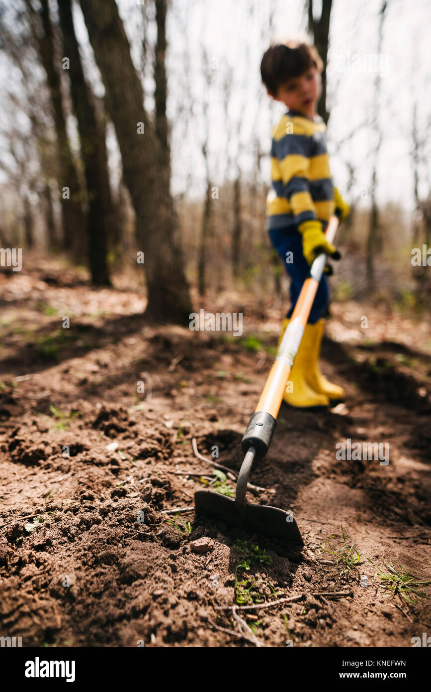 Boy digging the soil with a hoe Stock Photo