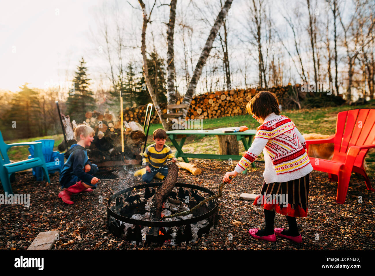 Three children sitting around a campfire Stock Photo