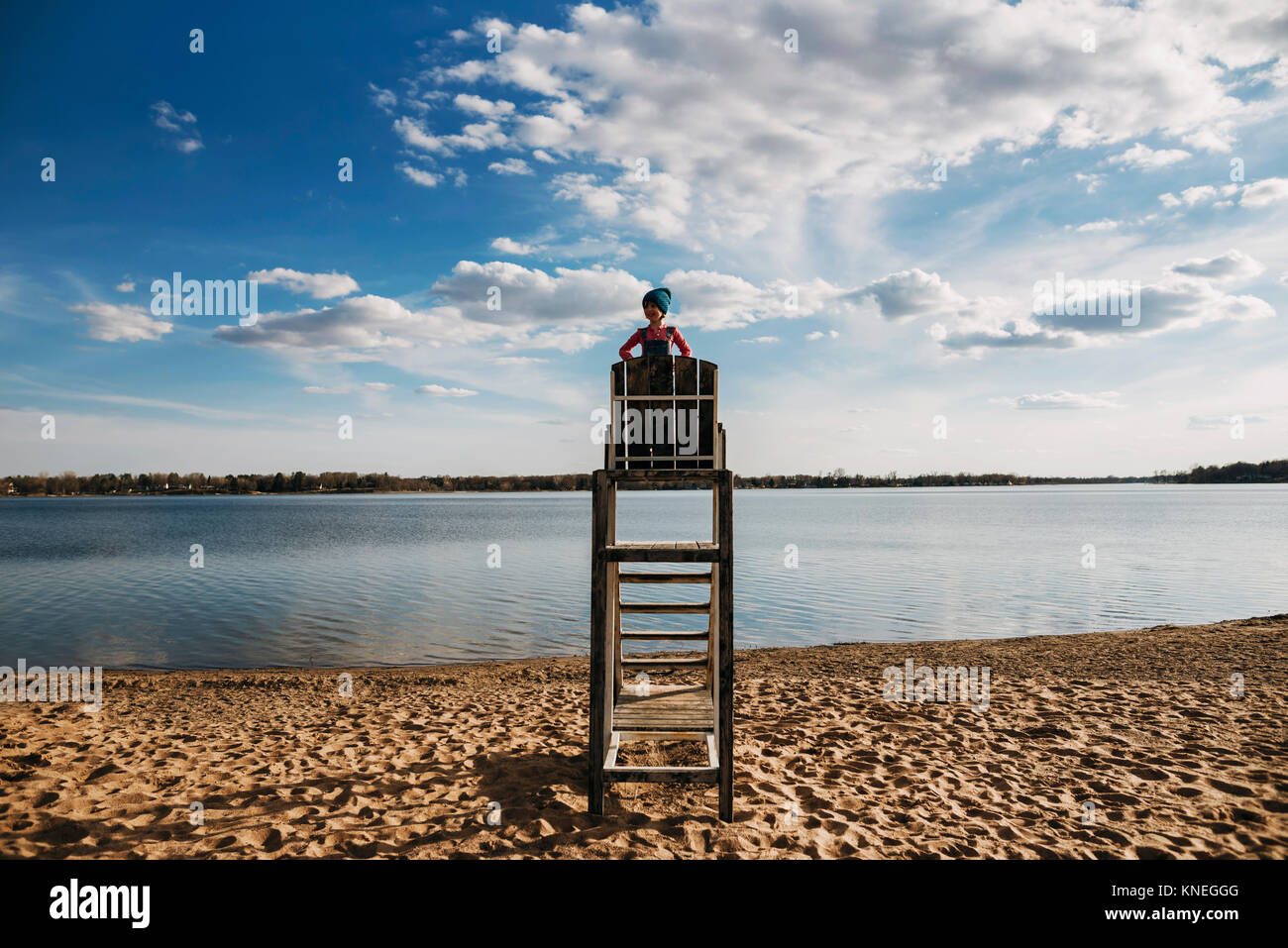 Girl standing on a lifeguard chair by a lake Stock Photo