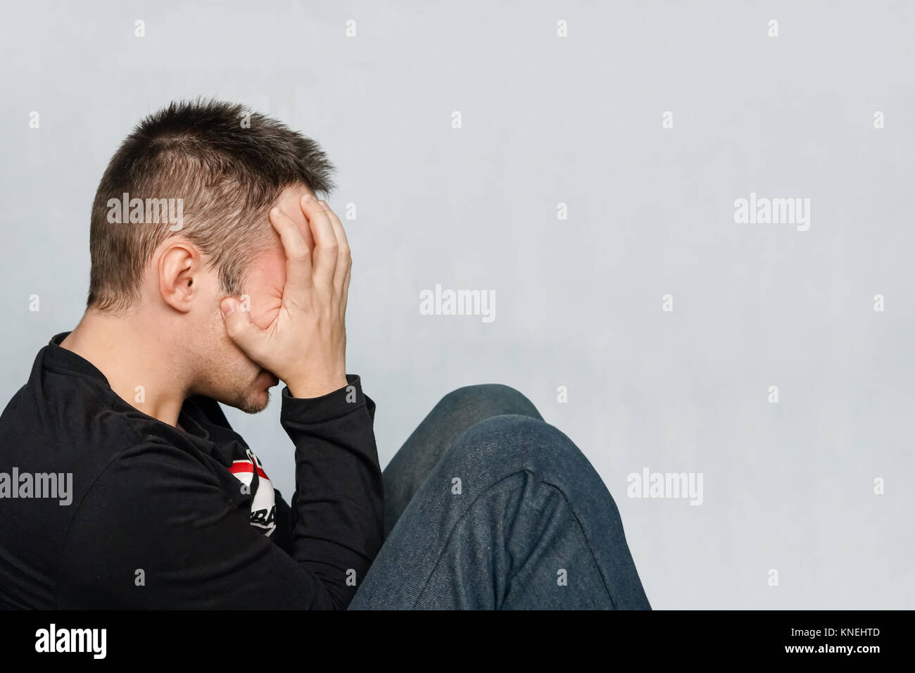 The depression man sit on the floor. Man with headache and fatigue. a sick man is hiding his face. hide the tears. fatigue, weariness, tiredness, lass Stock Photo