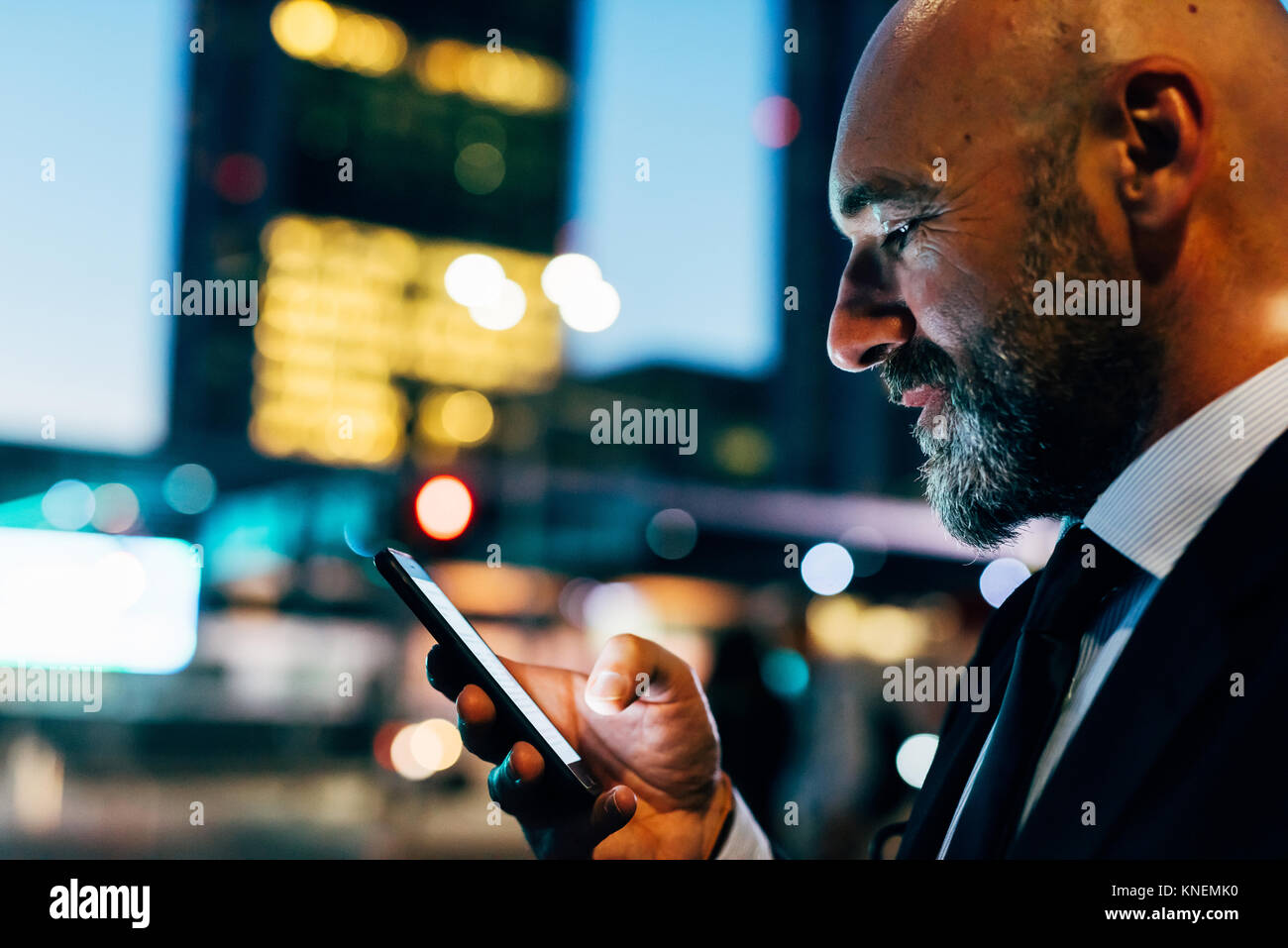 Mature businessman outdoors at night, using smartphone Stock Photo - Alamy