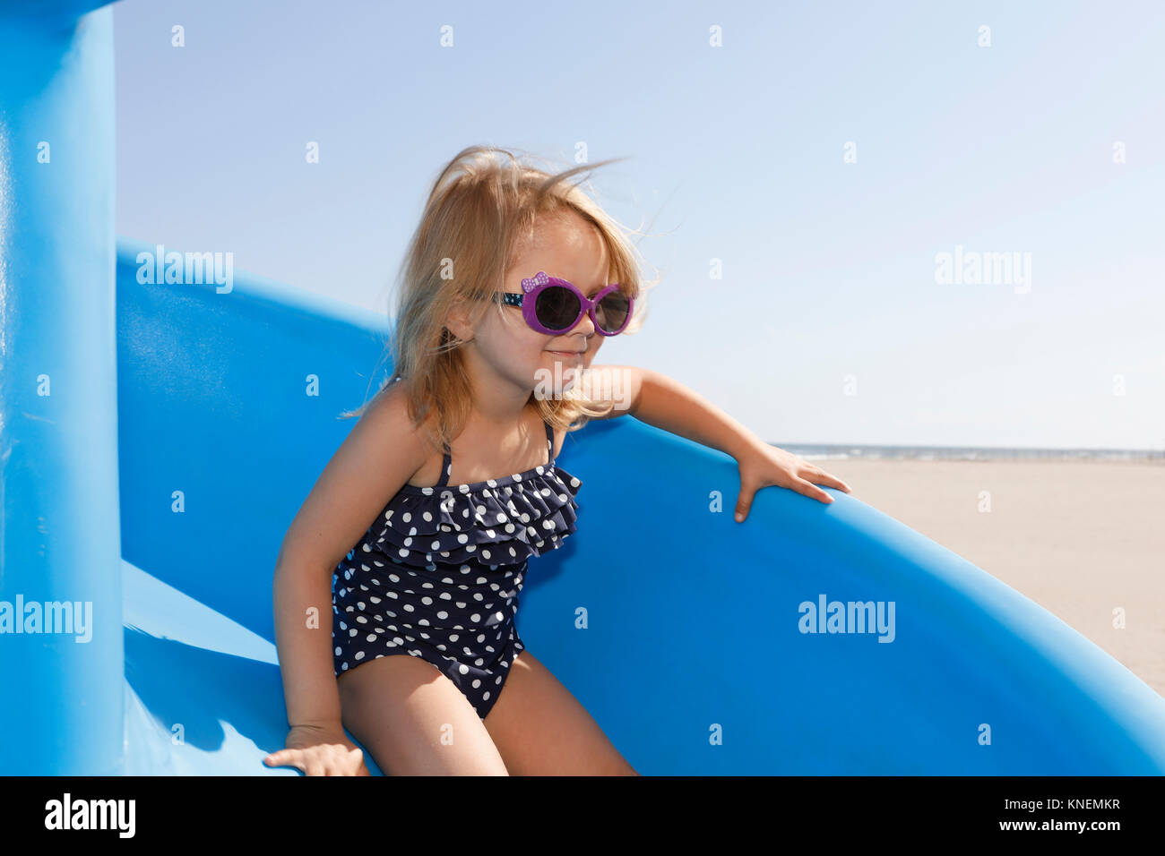 Girl on slide wearing swimming costume and sunglasses Stock Photo