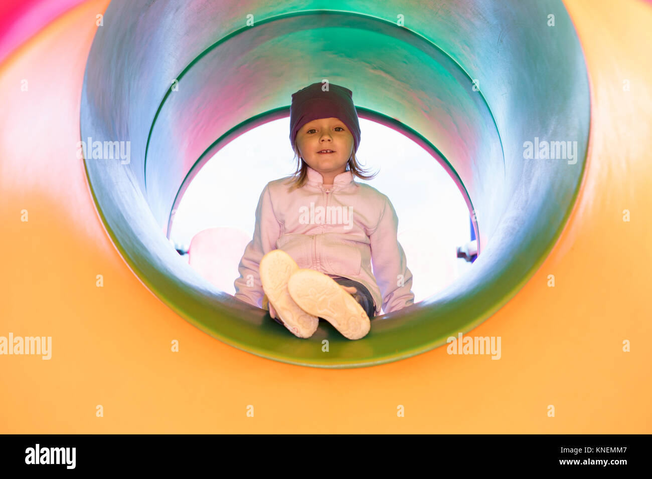 Girl in tube on climbing frame looking at camera smiling Stock Photo
