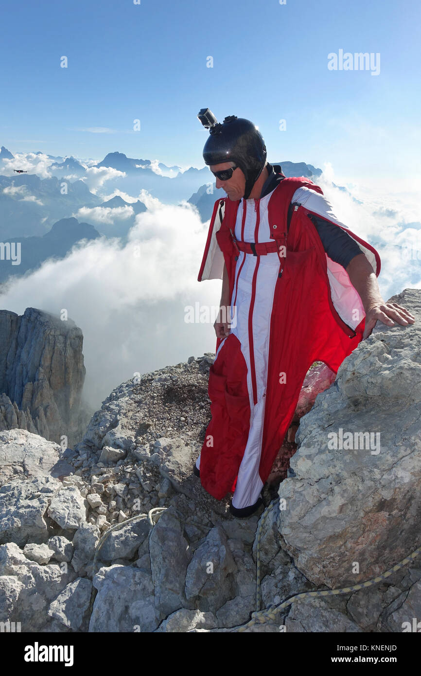 Male wingsuit BASE jumper preparing to fly from cliff edge Stock Photo