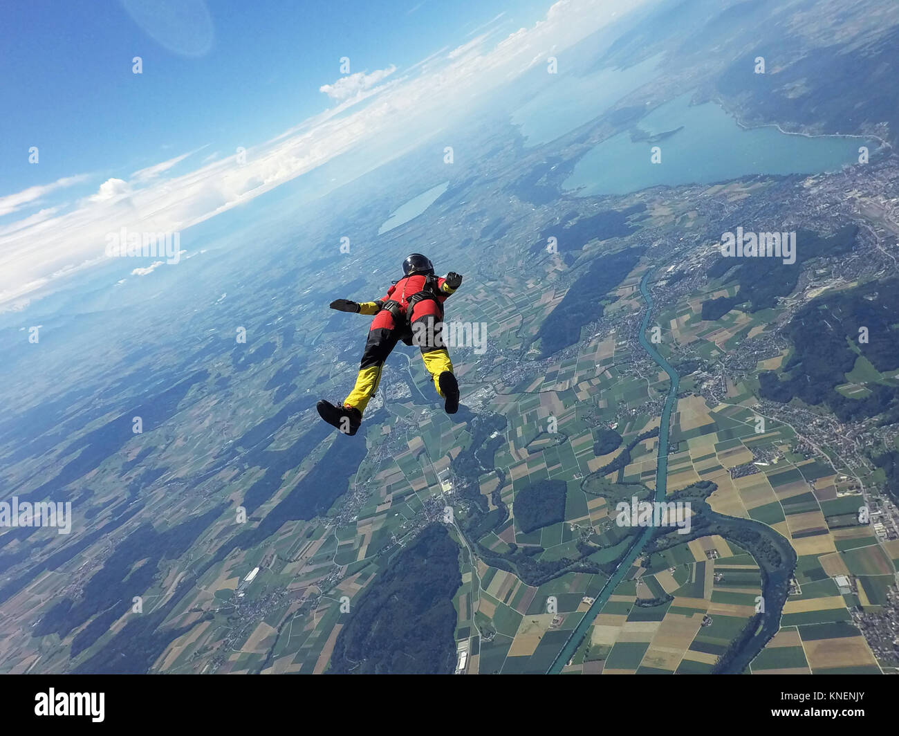 Female skydiver free falling on back above landscape Stock Photo