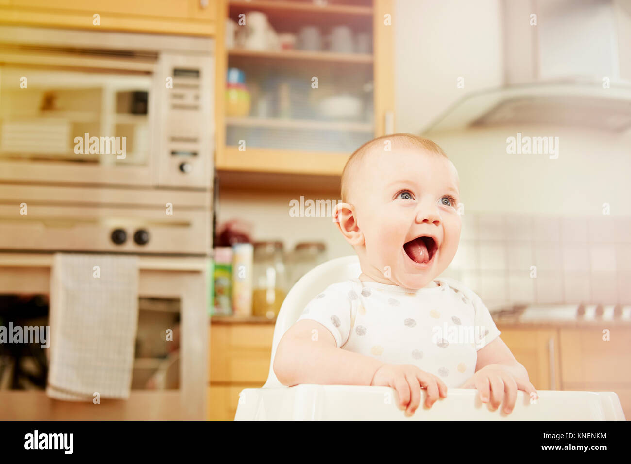 Baby boy sitting in high chair, laughing Stock Photo - Alamy