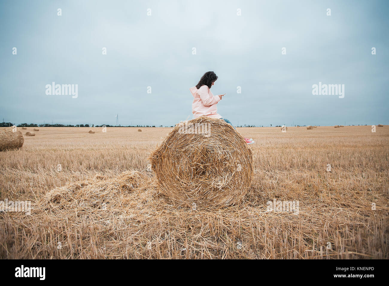 Woman in raincoat on hay bale, Odessa, Ukraine Stock Photo
