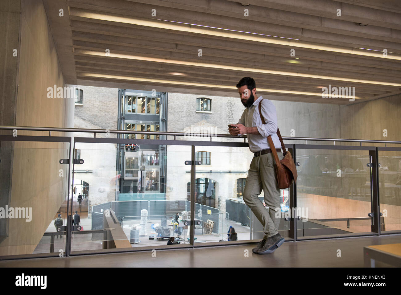 Man on mezzanine in office building texting on smartphone Stock Photo