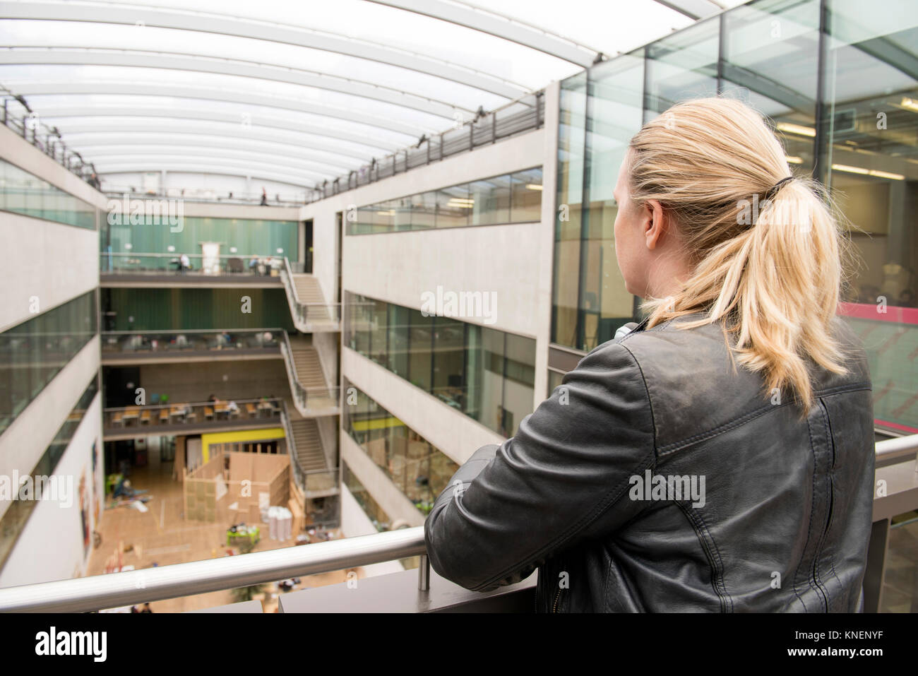 Rear view of woman on mezzanine of office building Stock Photo