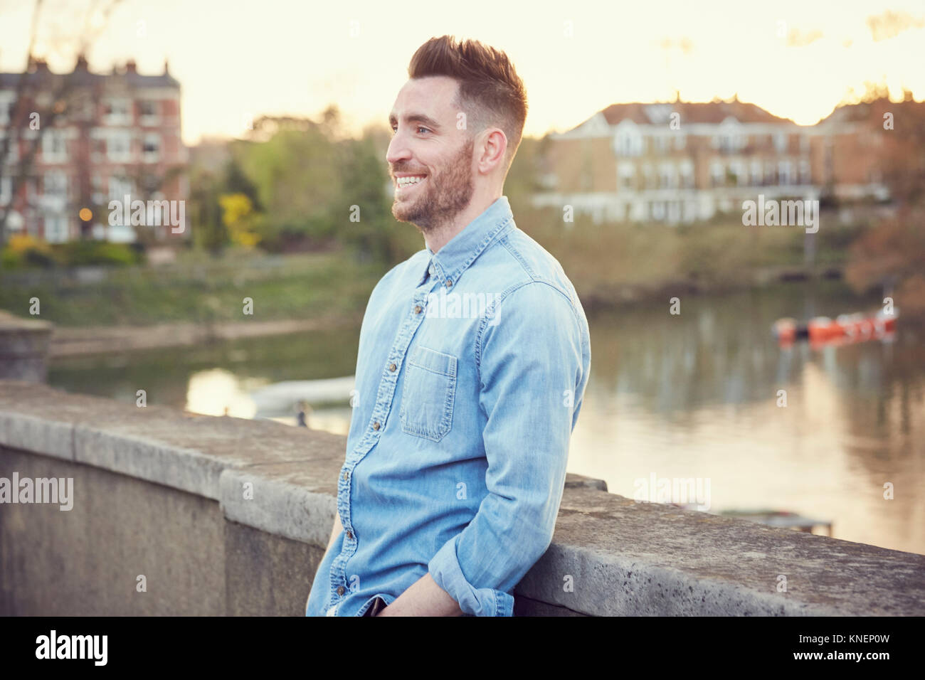 Bearded young man leaning against bridge over River Thames, Richmond, UK Stock Photo