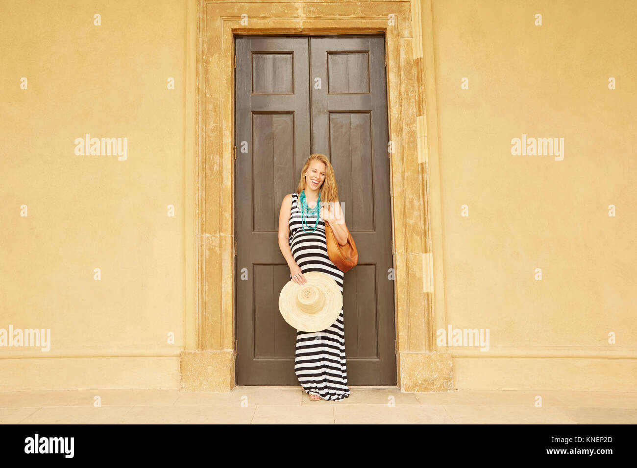 Pregnant woman posing against large double doors Stock Photo