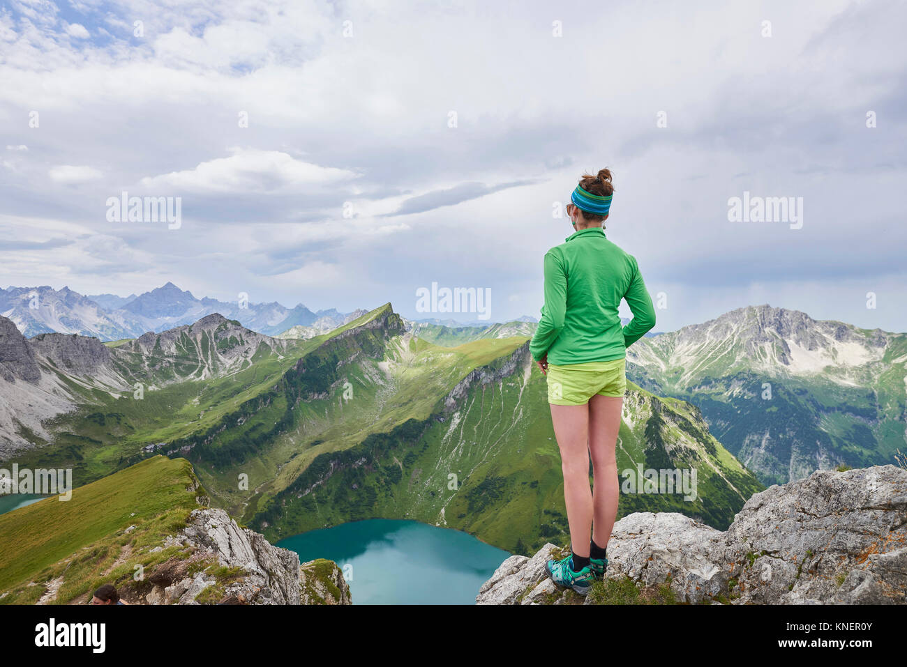 Rear view of female hiker on rocky edge looking out over Tannheim mountains, Tyrol, Austria Stock Photo