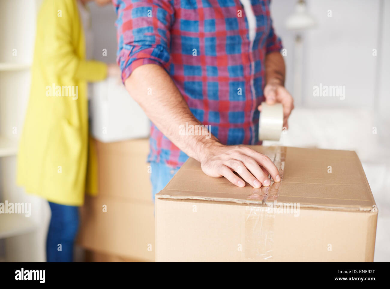 Young couple moving home, young man taping up cardboard box, mid section Stock Photo