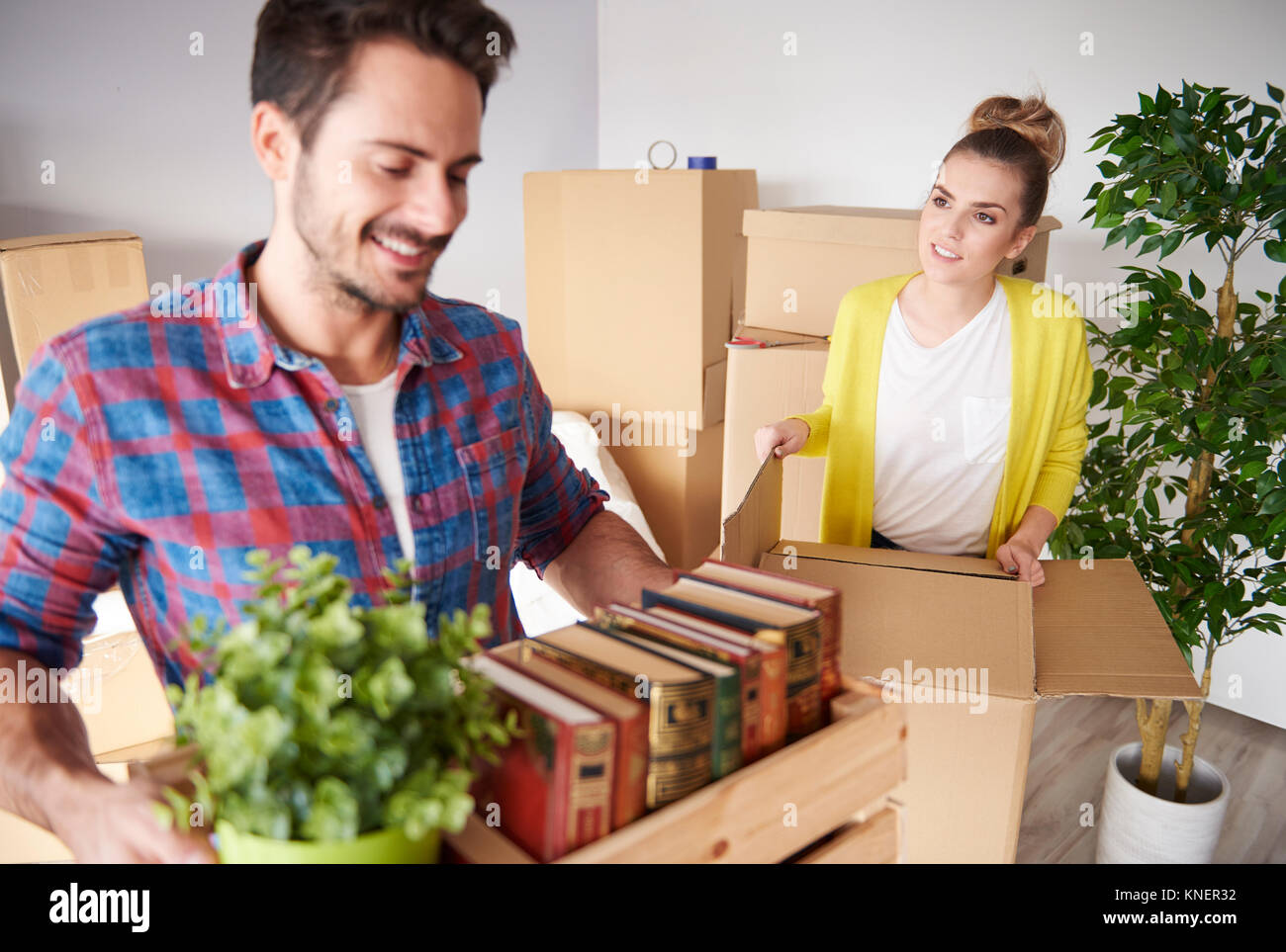 Young couple moving home, packing belongings into cardboard boxes Stock