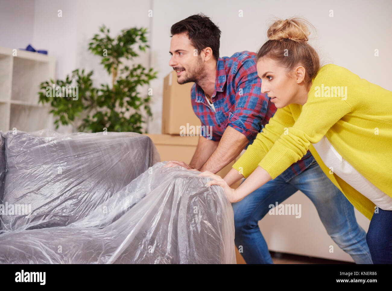 Young couple in new home, moving furniture around Stock Photo Alamy