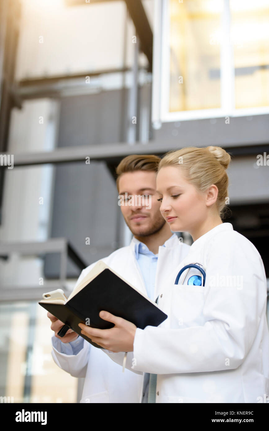 Male and female doctor looking through book Stock Photo