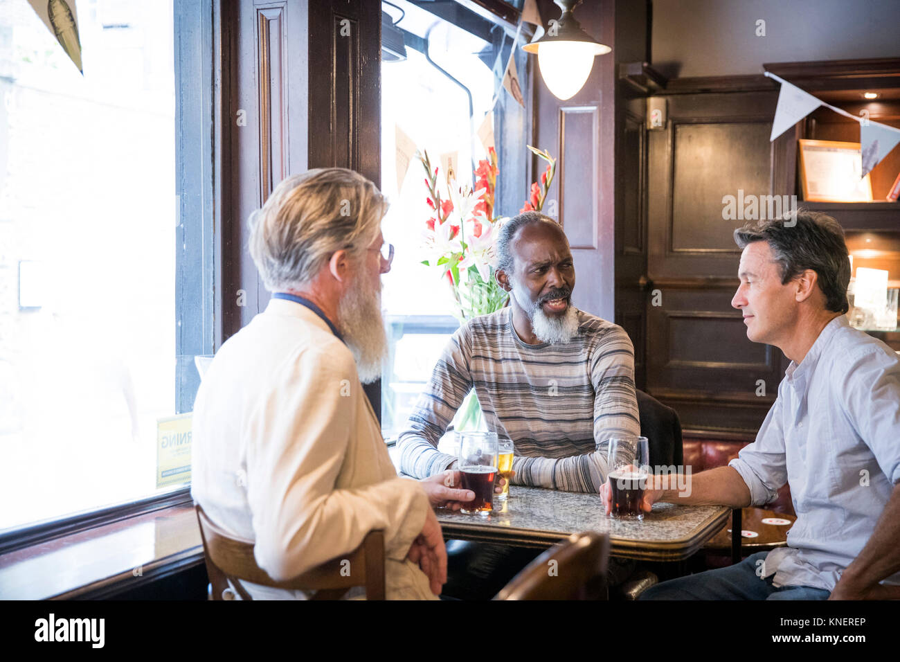 Three mature men, sitting together in pub, talking Stock Photo