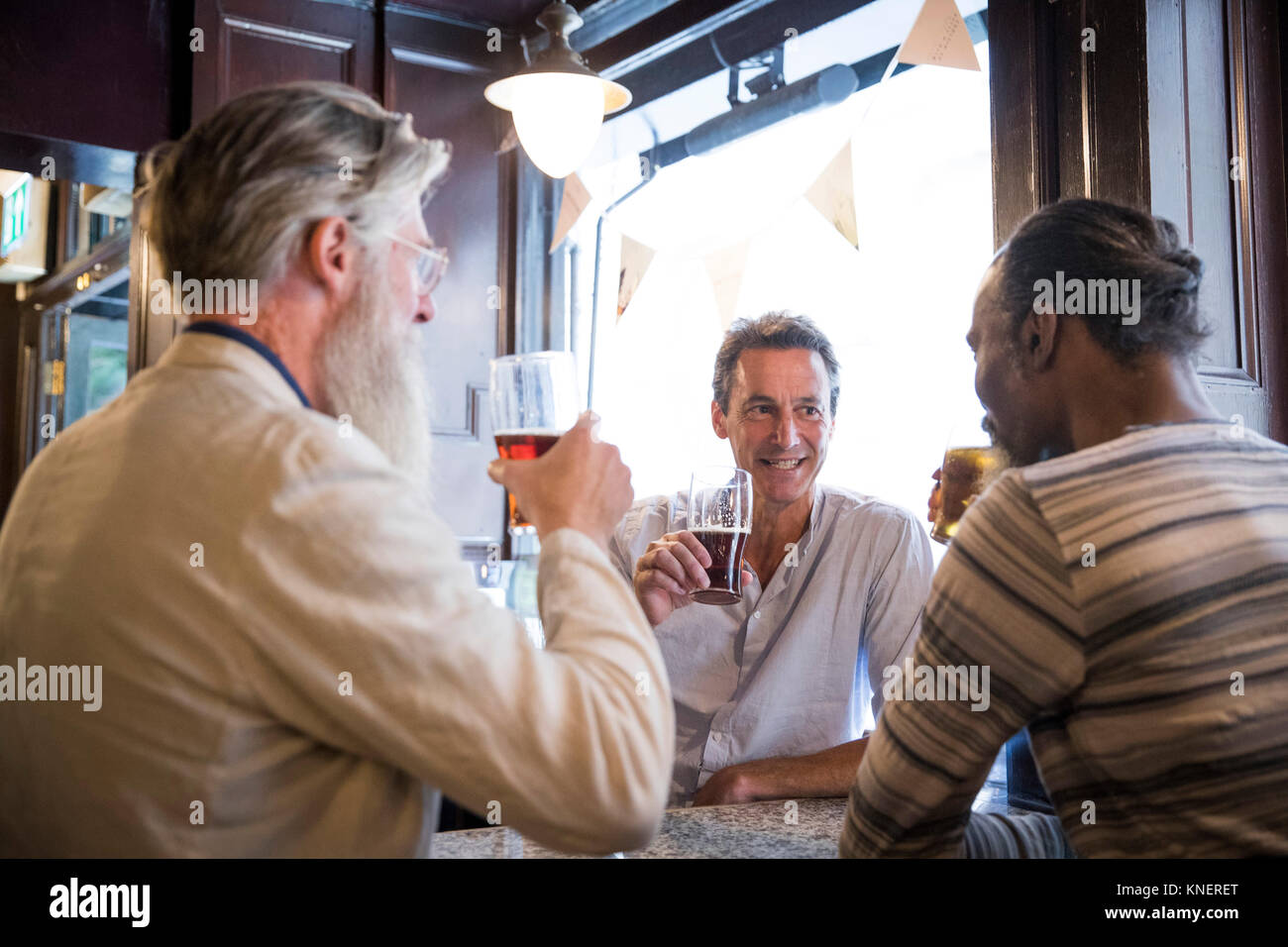 Three mature men, sitting together in pub, talking Stock Photo