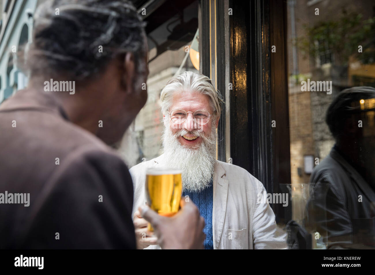 Two mature men, standing outside pub, drinking beer Stock Photo