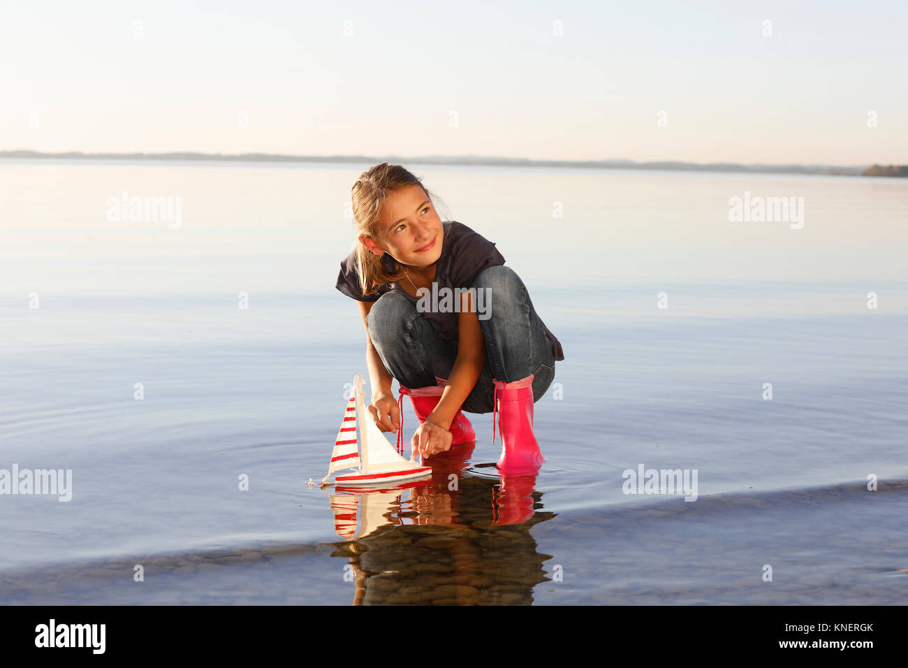 Young girl floating toy boat on water Stock Photo
