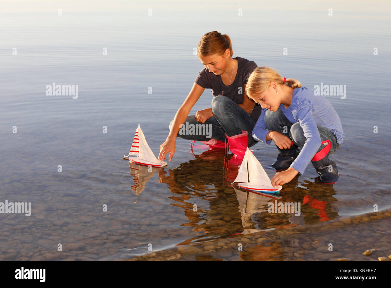 Two young girls floating toy boats on water Stock Photo