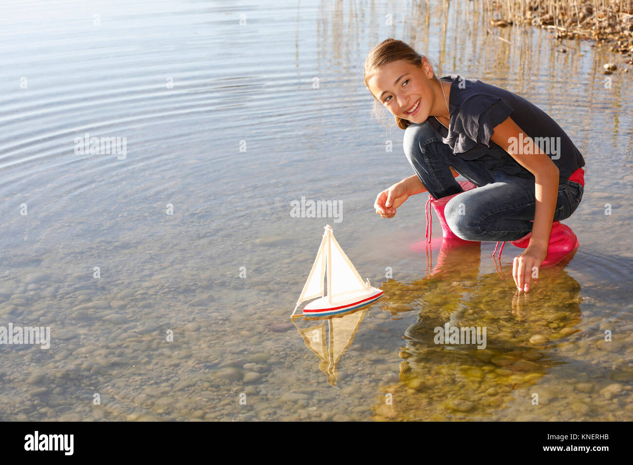 Young girl floating toy boat on water Stock Photo
