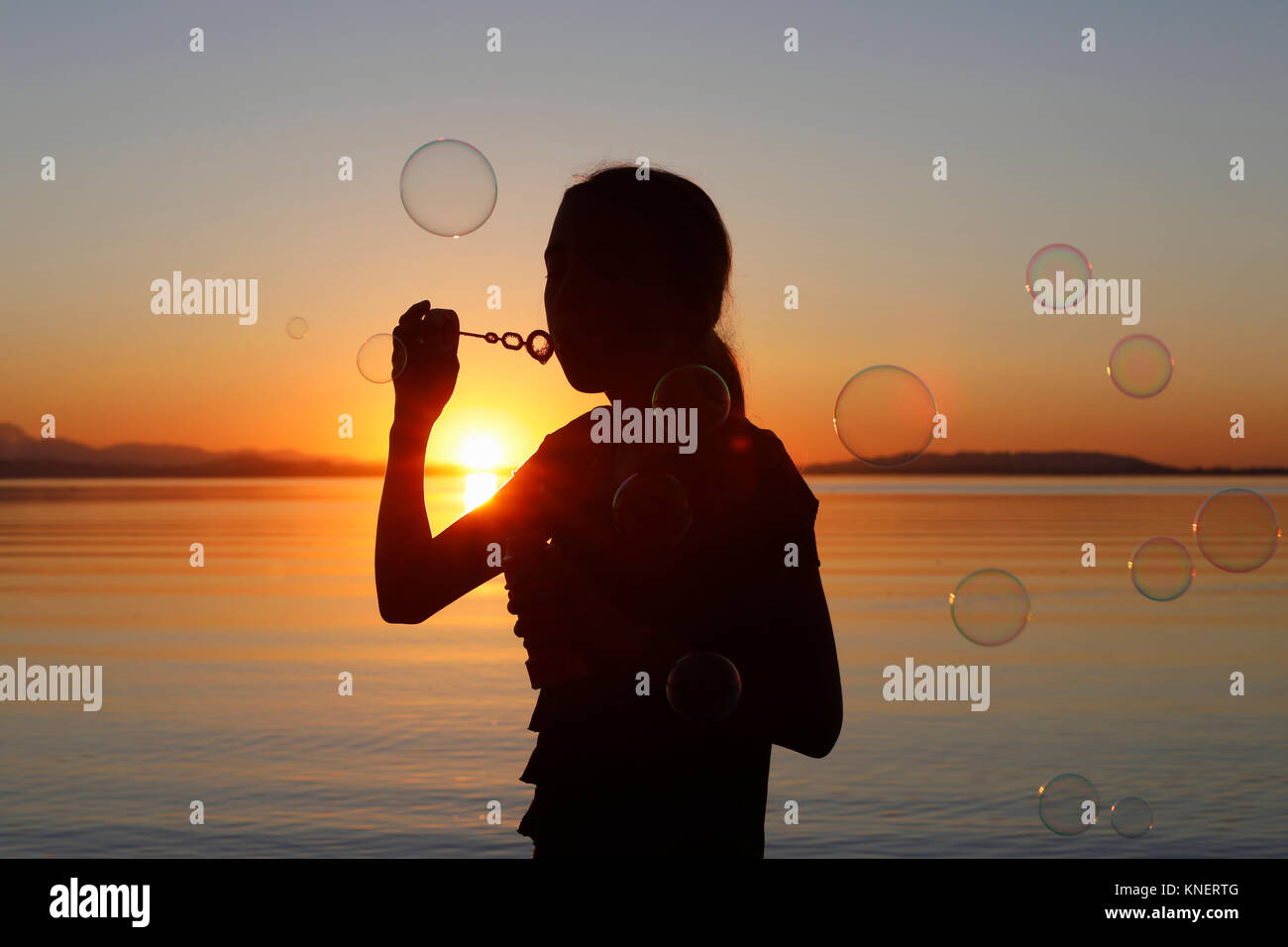 Young girl, outdoors, blowing bubbles, at sunset Stock Photo