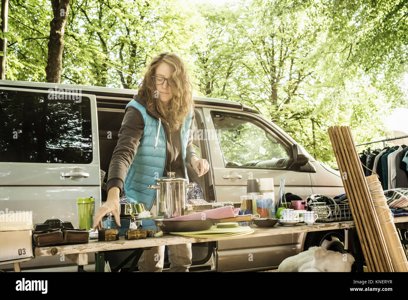 Female stall holder placing second hand goods on stall at forest flea market Stock Photo