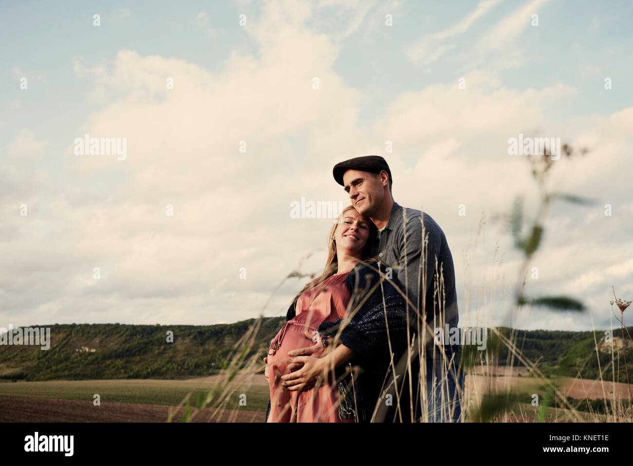 Portrait of happy pregnant mid adult couple in fields Stock Photo