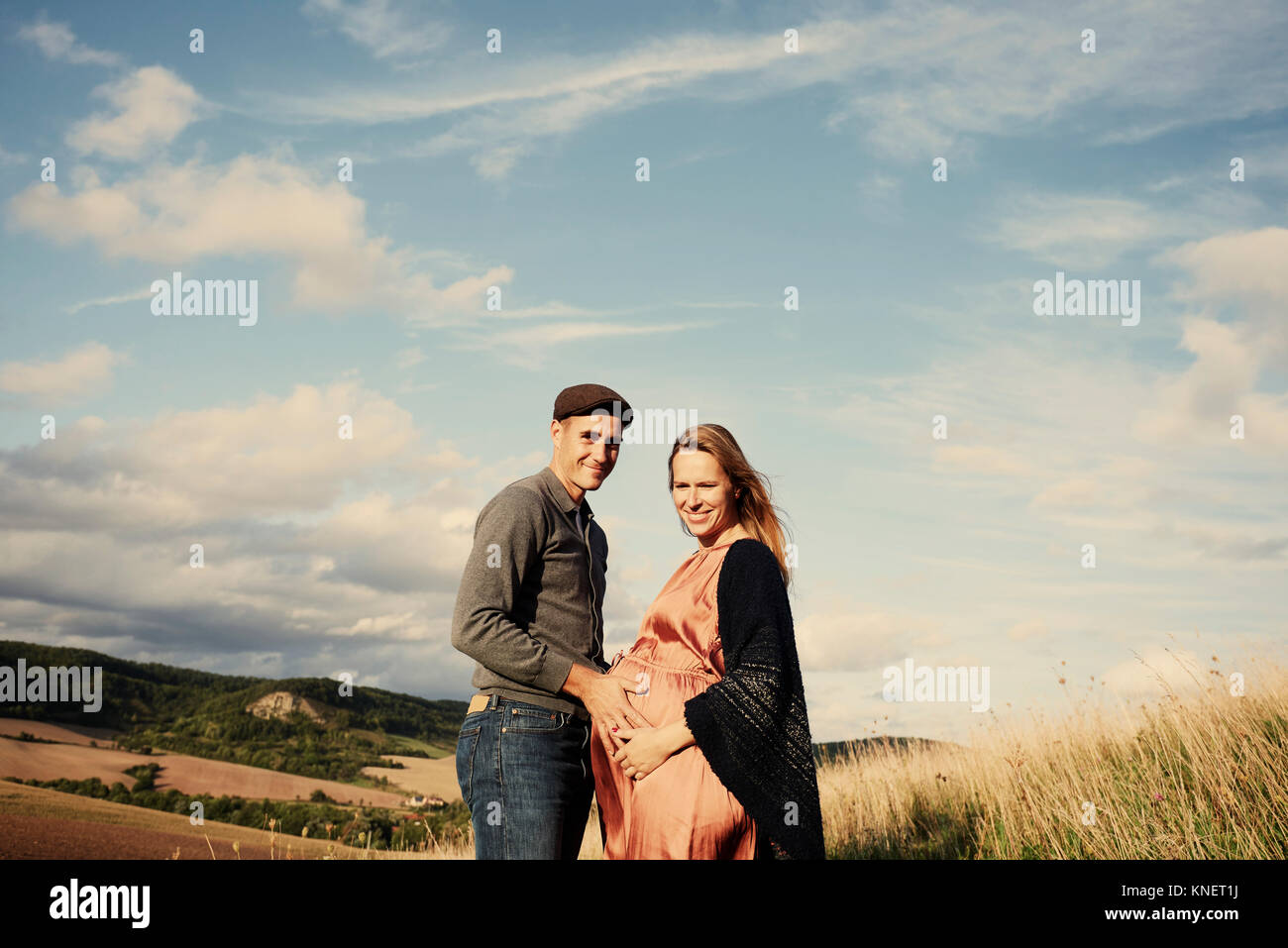 Portrait of pregnant mid adult couple on rural hillside Stock Photo