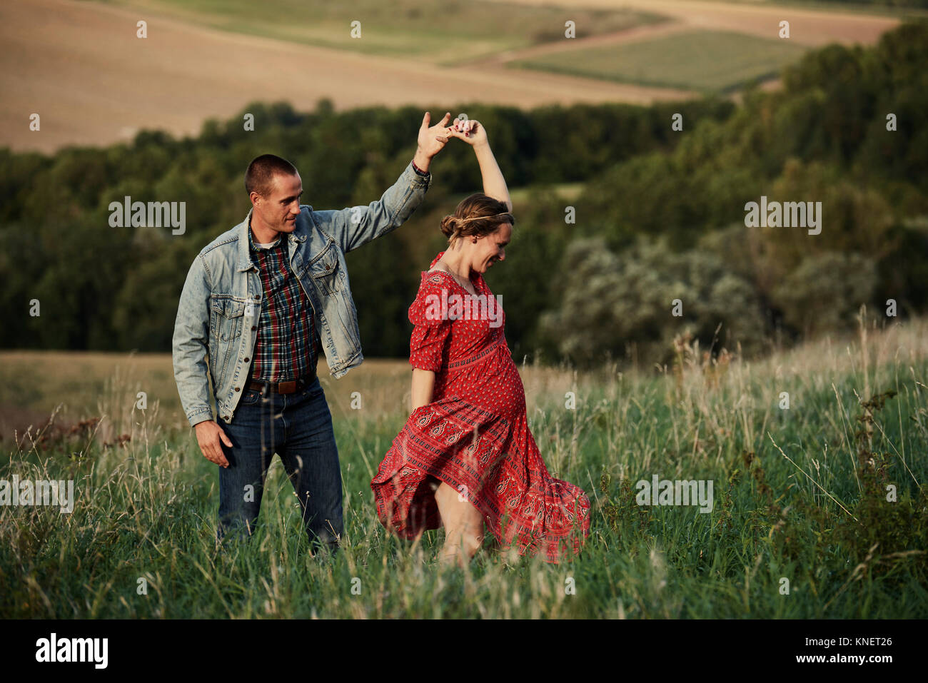Romantic pregnant mid adult couple dancing in field Stock Photo